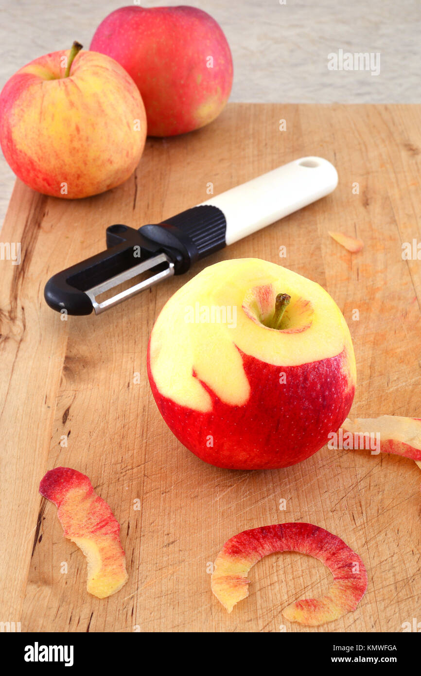 Gala Apfel mit Schäler im Hochformat. Selektiver Fokus auf Apple. In natürlichem Licht gedreht. Stockfoto
