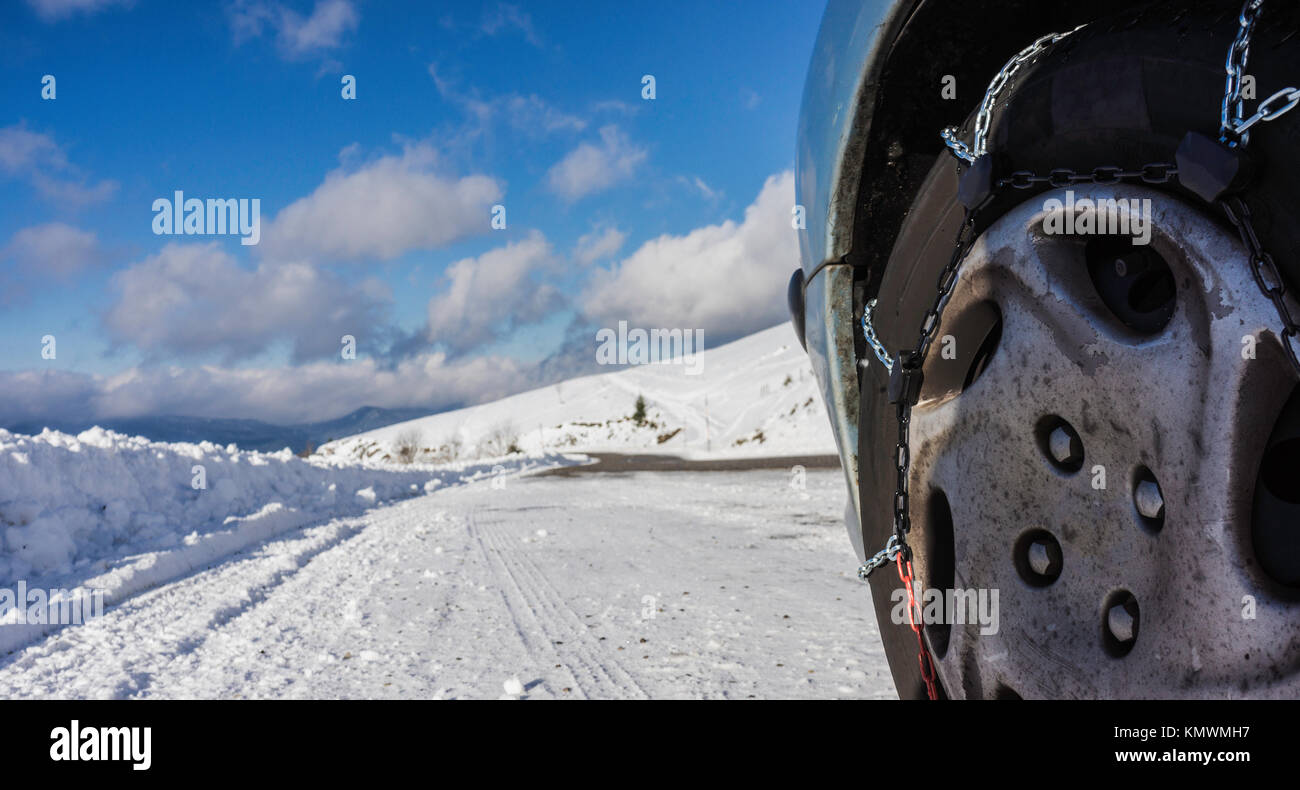 Nahaufnahme von Schneeketten montiert auf einem verschneiten Auto Rad mit großen Kopie Raum auf der linken Seite. Stockfoto