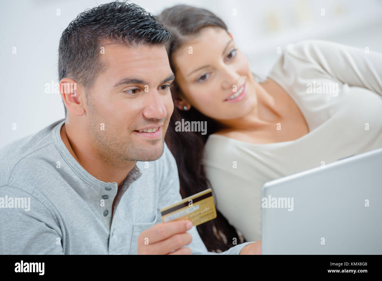 Glückliches Paar mit Kreditkarte und Laptop zu Hause Stockfoto