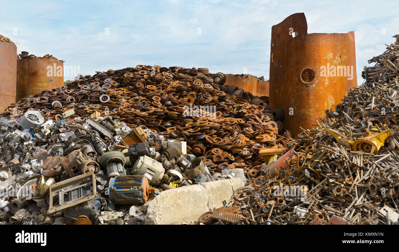 Recycling Center mit Ballen von Metall- und Kran mit Greifer werfen Lkw und rostige Räder Stockfoto
