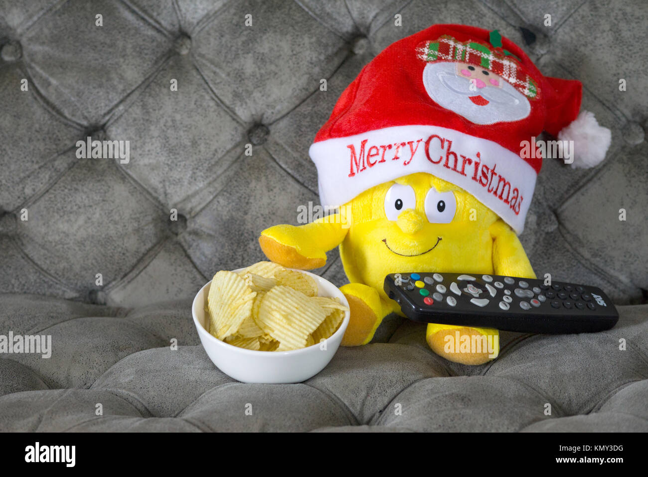 Konzept Bild eines festliche Weihnachten fernsehen - Soft Toy mit Fernbedienung und Schüssel Chips. Stockfoto