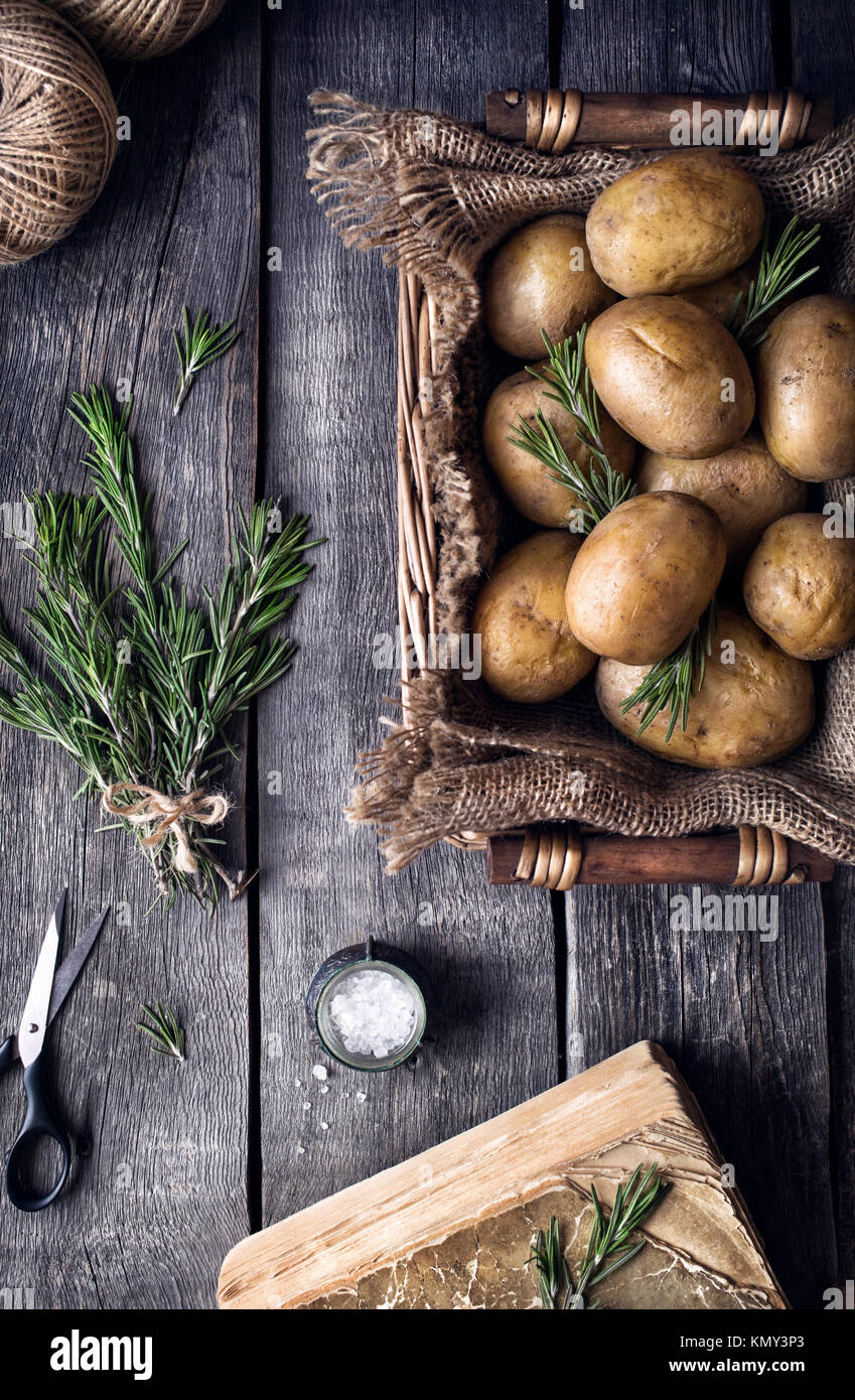 Kartoffeln mit Rosmarin auf rustikalen Holzmöbeln Hintergrund aus der Sicht von oben Stockfoto