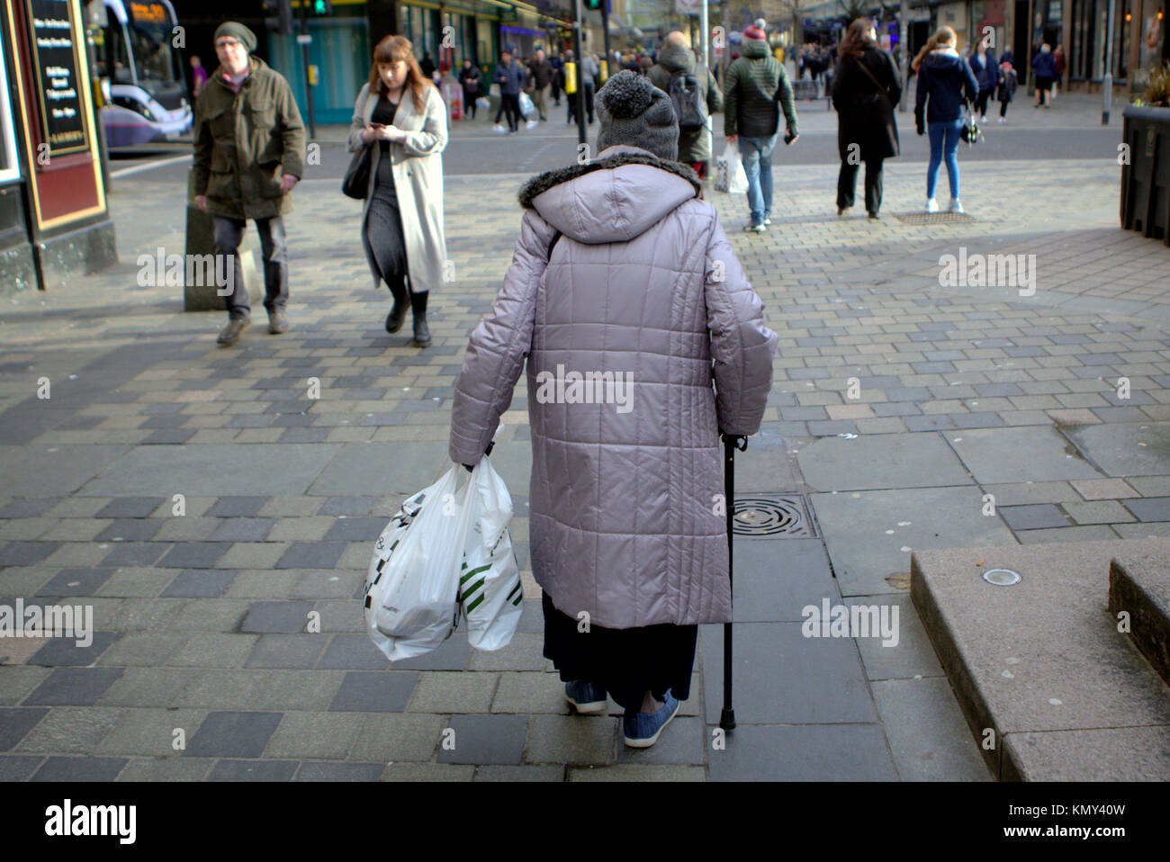 Alte Dame älterer Bürger kämpfen mit Stock und Einkaufstaschen aus gesehen hinter auf der Sauchiehall Street Fußgängerzone Glasgow Stockfoto