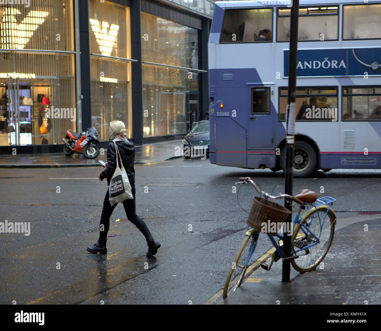 Stilvolle Mädchen Frau Überqueren der Straße Fahrrad und Bus Konflikt Armani shop Zeichen aus gesehen hinter der Kreuzung der Ingram Street und Hanover Street Stockfoto