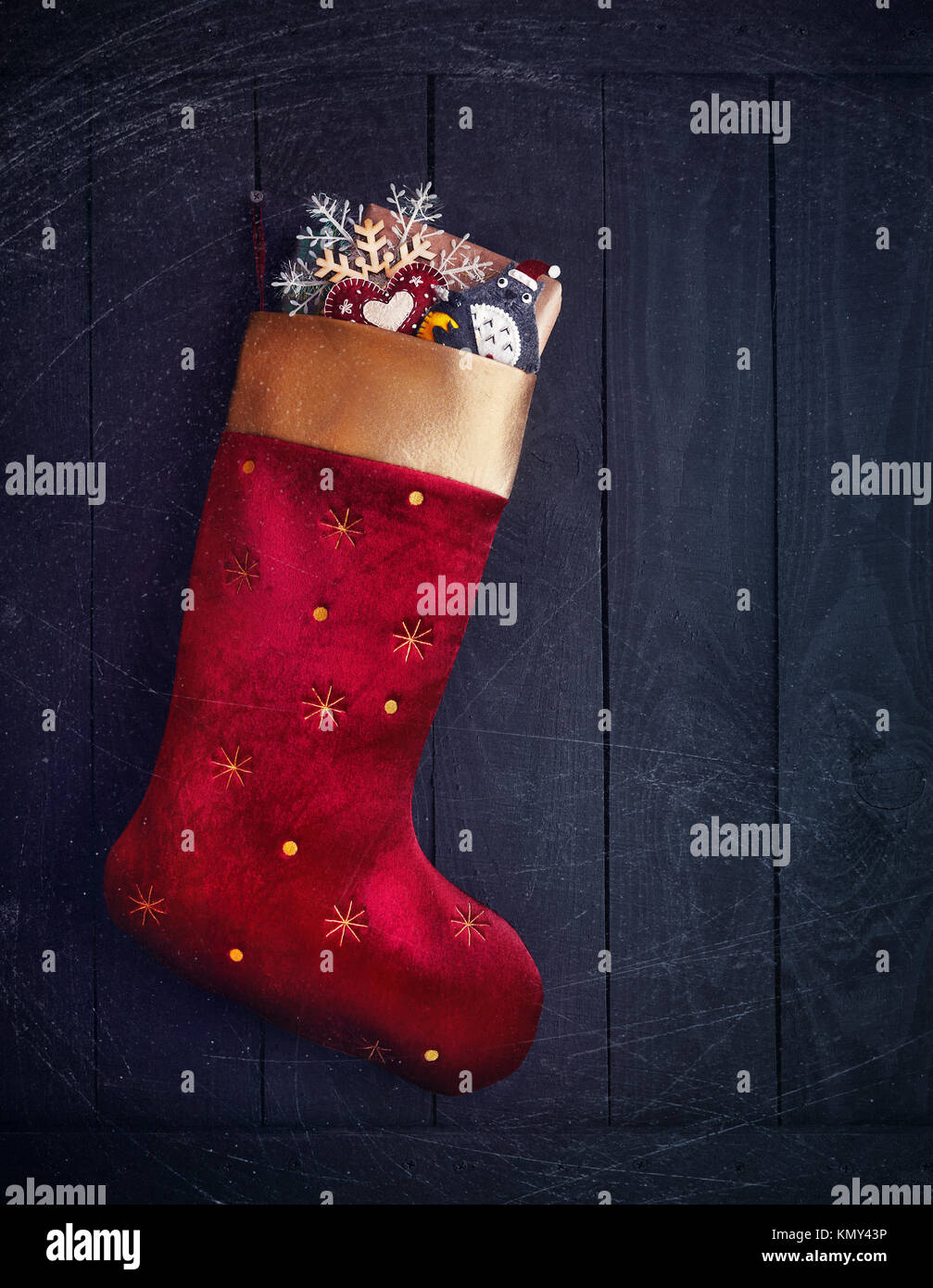 Rote Strumpf mit Geschenken und Spielsachen auf hölzernen Hintergrund auf Weihnachten Stockfoto