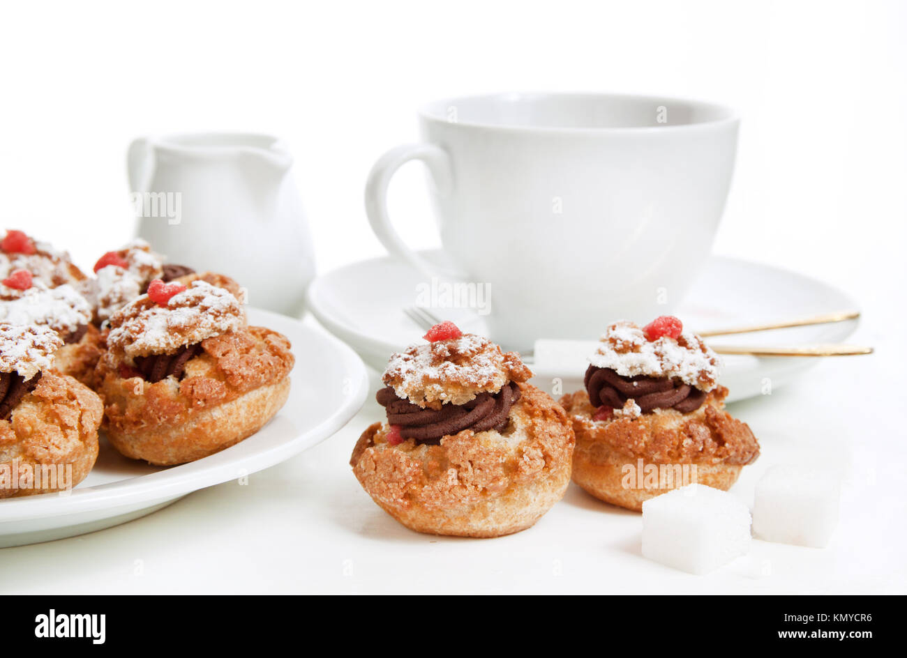 Mini-Kuchen mit Schokoladenmousse serviert mit Tasse Tee über Weiß Stockfoto