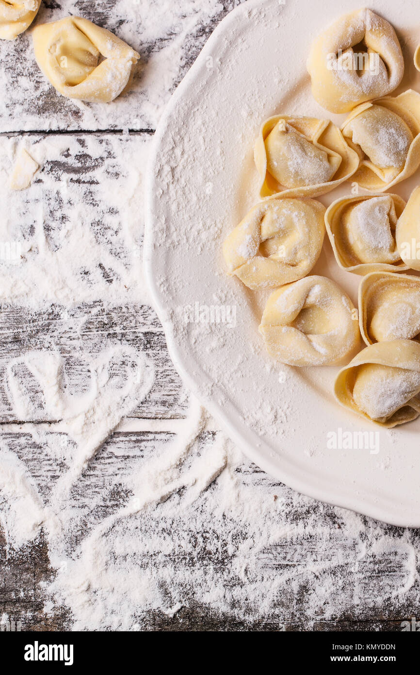 Draufsicht auf Teller hausgemachter Pasta Ravioli über Holztisch mit Mehl. Serien ansehen Stockfoto