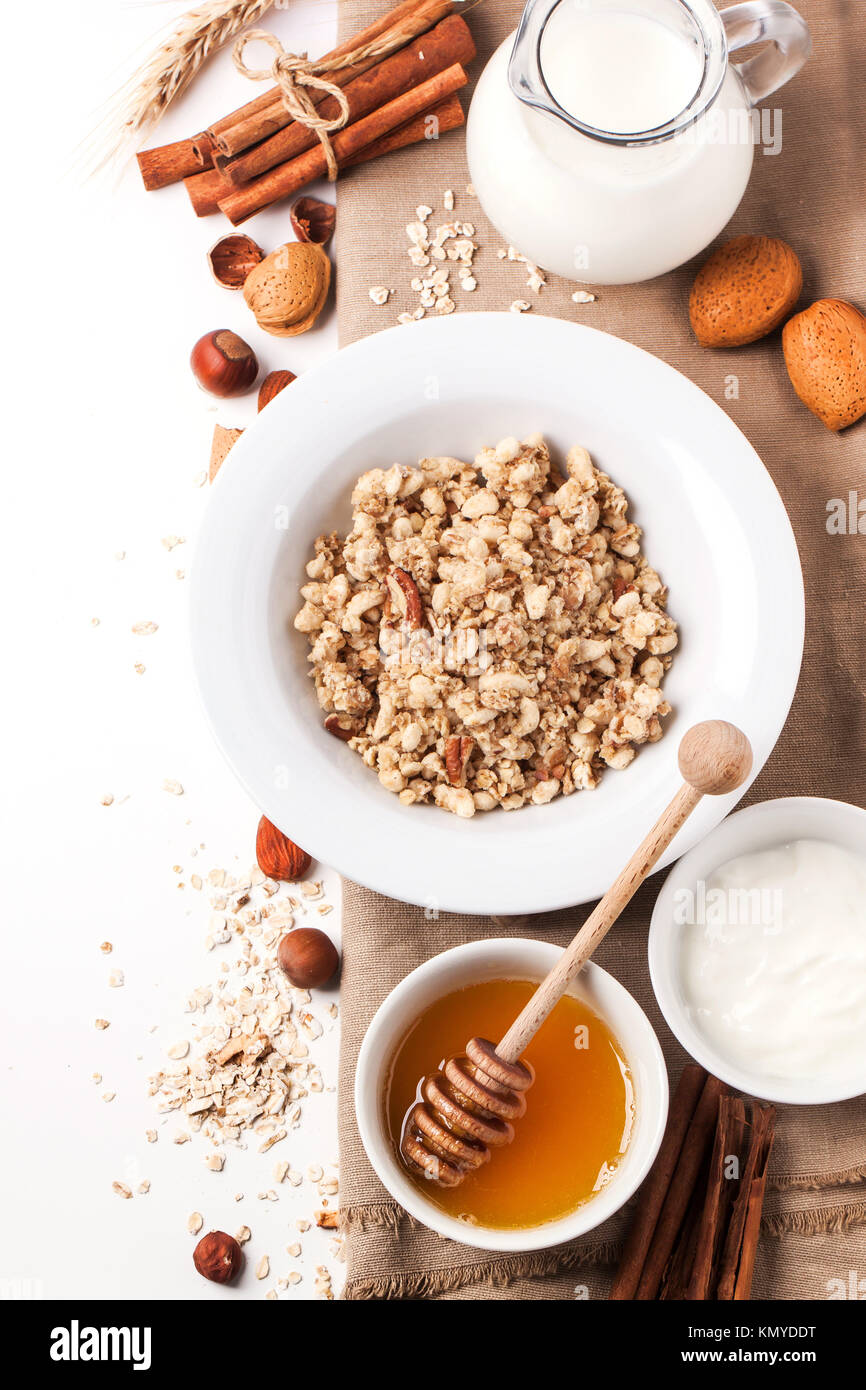 Draufsicht auf Teller Müsli mit Milch, Honig, Zimt und Nüssen über weiß. Serien ansehen Stockfoto