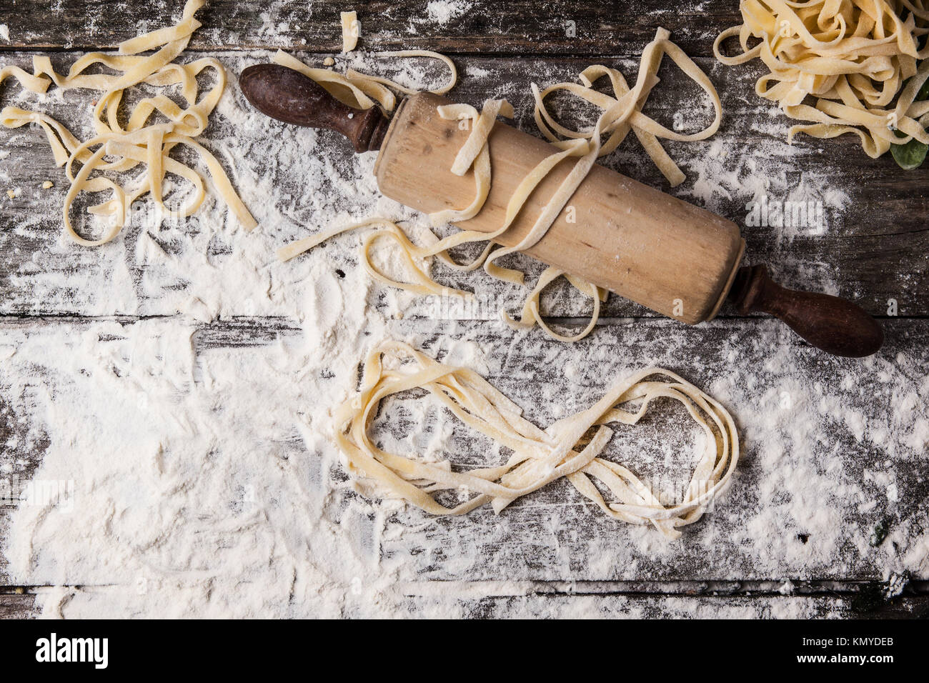 Draufsicht auf raw hausgemachte Pasta mit Mehl, vintage Rolling Pin und Infinity Symbol über dem alten Holztisch Stockfoto