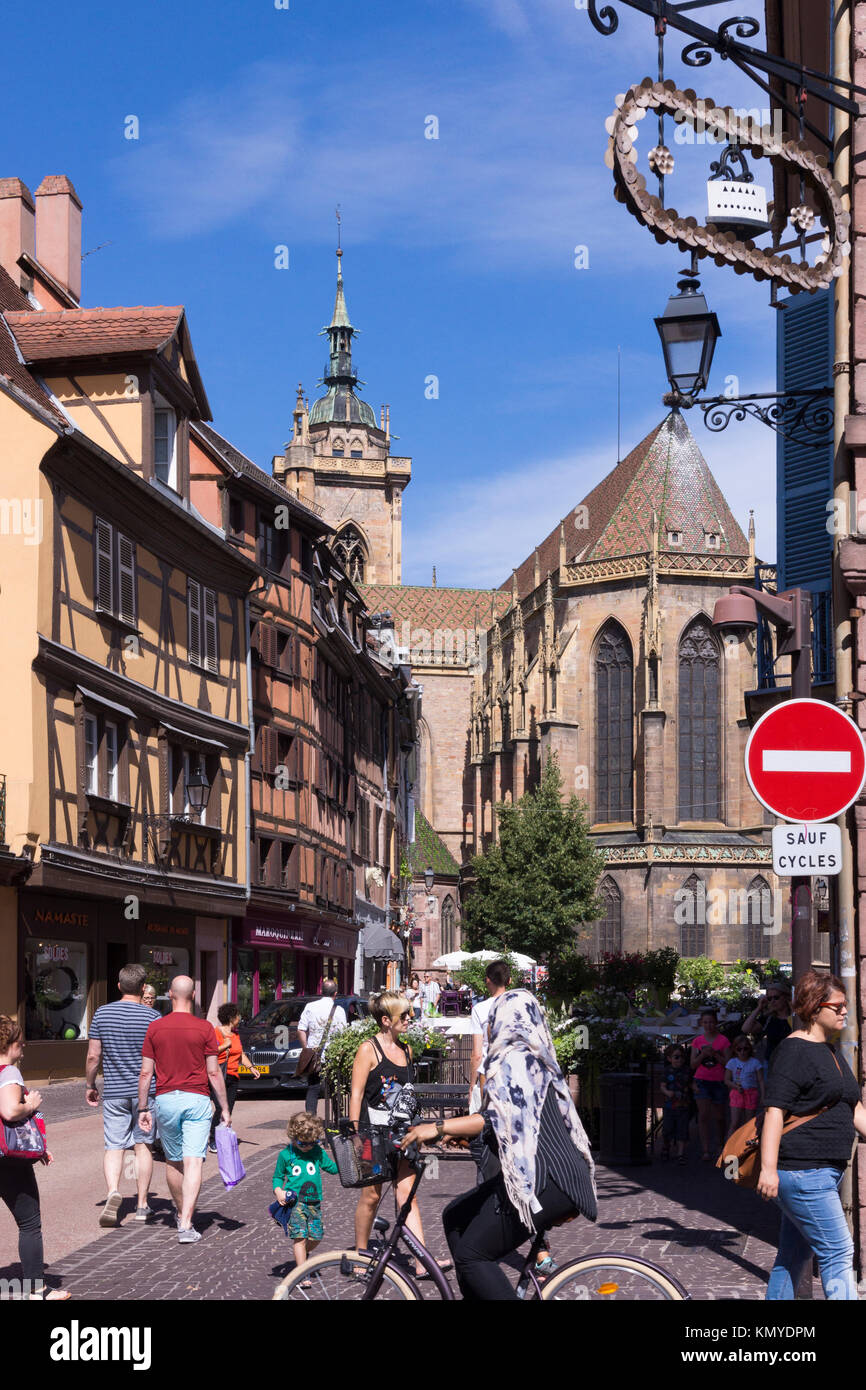 Touristen in der Rue de l'Eglise mit traditionellen Maisons à Colombages (Fachwerkhäuser) und der Kirche Saint Martin in Colmar, Elsass, Frankreich Stockfoto