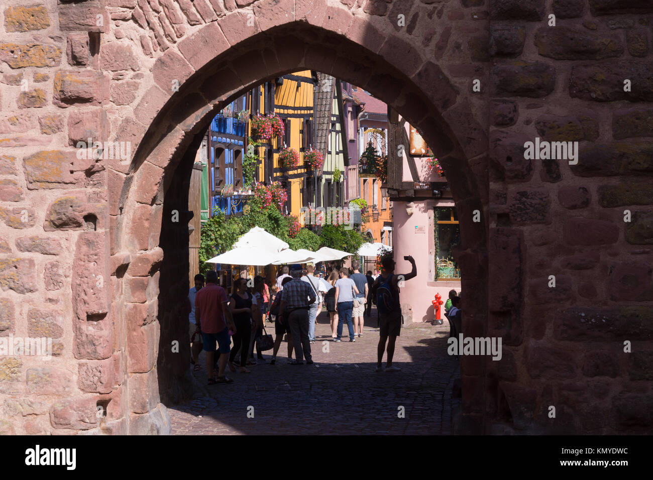 Touristen, die durch das Obertor (Oberes Tor) in das 16. Jahrhundert Stadt Riquewihr auf der beliebten Elsässischen Weinstraße Stockfoto