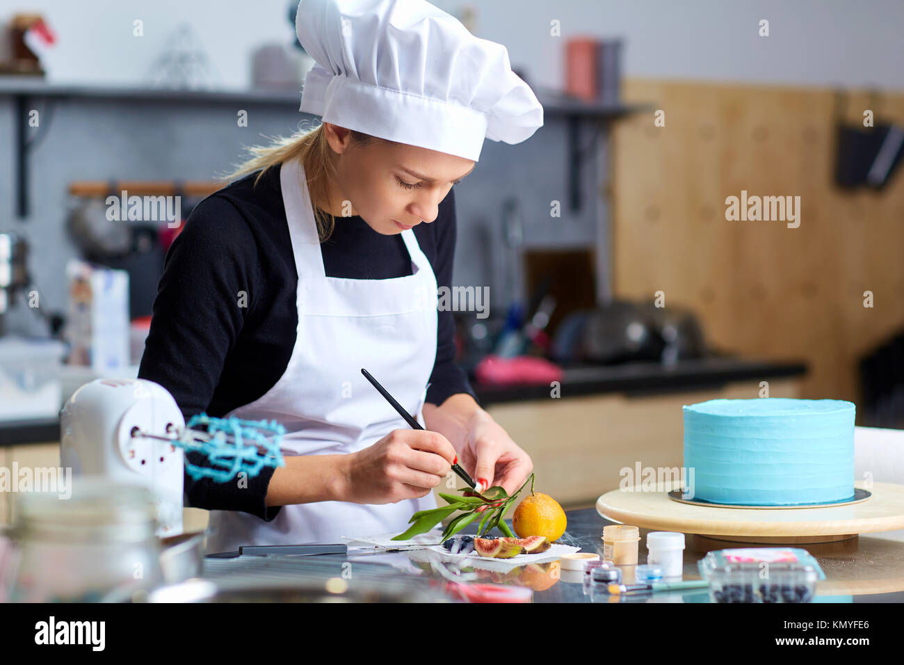 Ein konditor Frau schmückt ein Kuchen auf dem Tisch in der Küche. Stockfoto