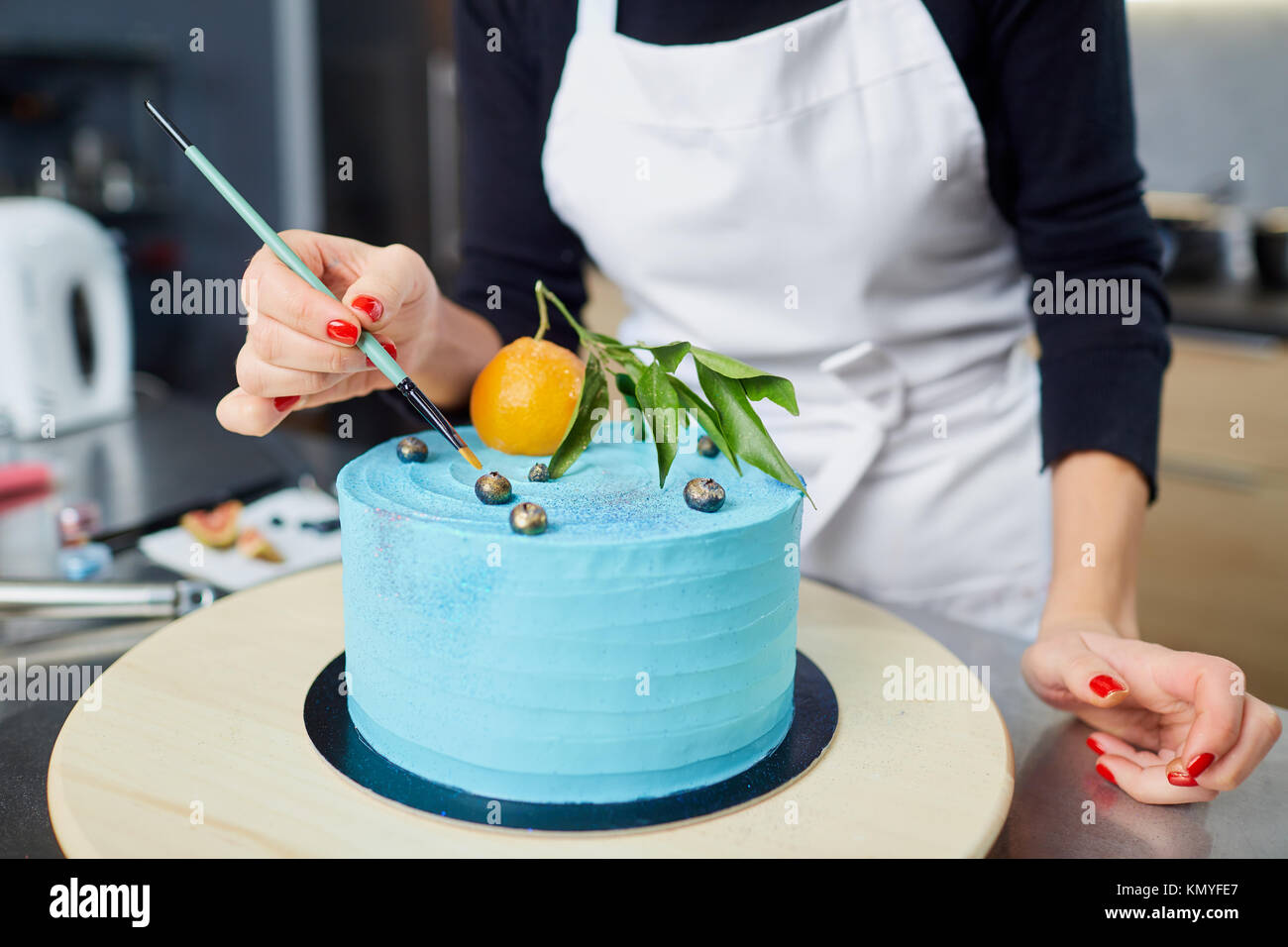 Der Konditor schmückt den Kuchen auf den Tisch in der Küche. Stockfoto
