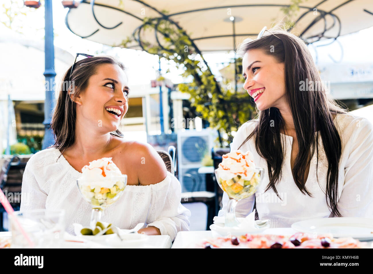 Zwei schöne junge Frauen lächelnd und mit einem Obstsalat in Einem Stockfoto