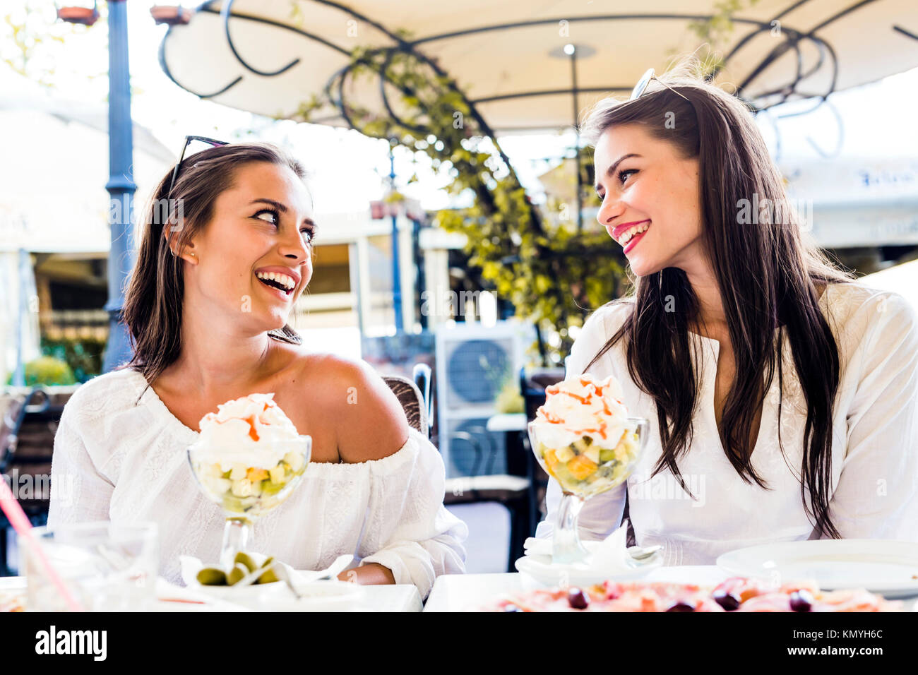 Zwei schöne junge Frauen lächelnd und mit einem Obstsalat in Einem Stockfoto