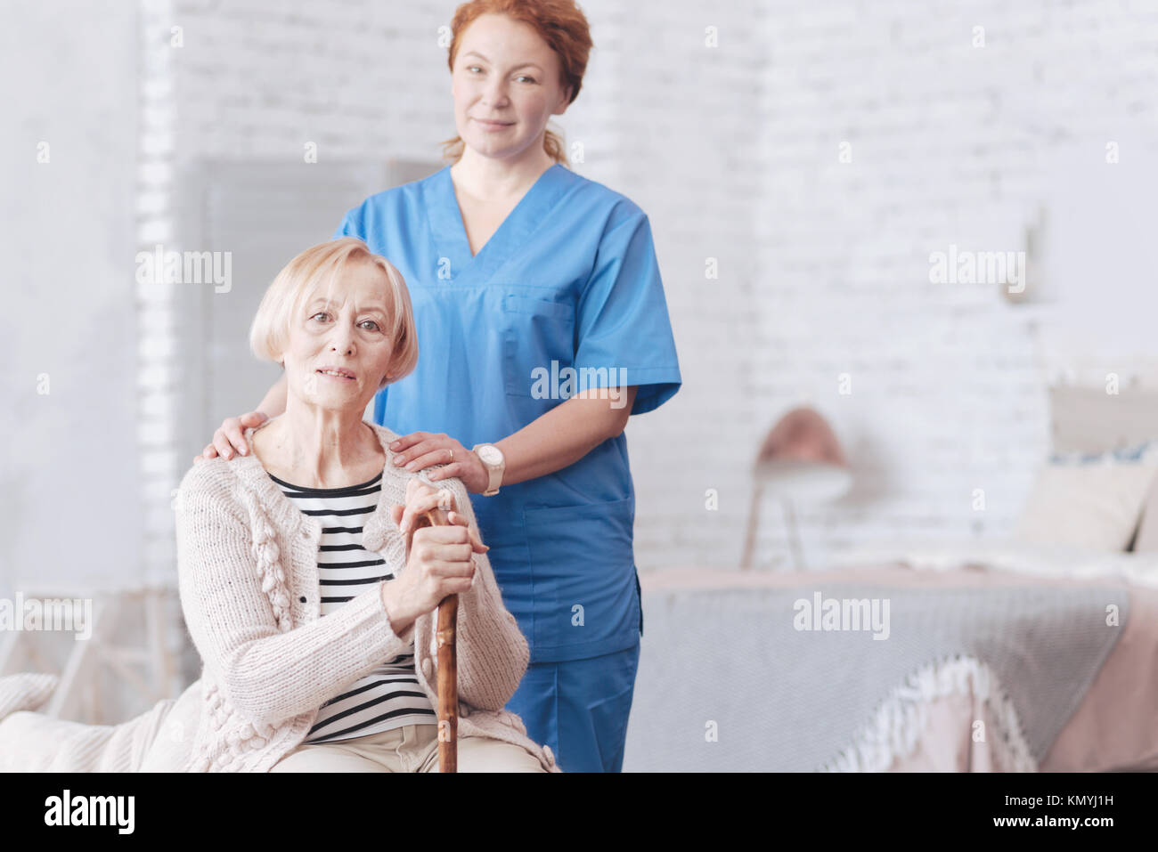 Eingedenk weibliche Betreuer neben Ihrem älteren stehenden Patienten Stockfoto