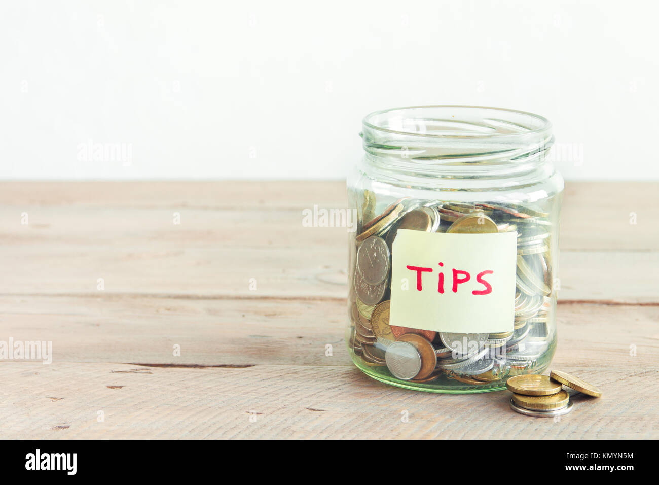 Münzen in Glas Glas mit Tipps label. Geld sparen, Tipps und Spendenkonzept, kopieren. Stockfoto