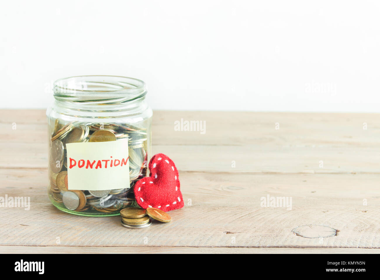 Münzen in Glas Glas mit Spende label und roten Herzen. Kosteneinsparungen, Nächstenliebe und Spendenkonzept, kopieren. Stockfoto