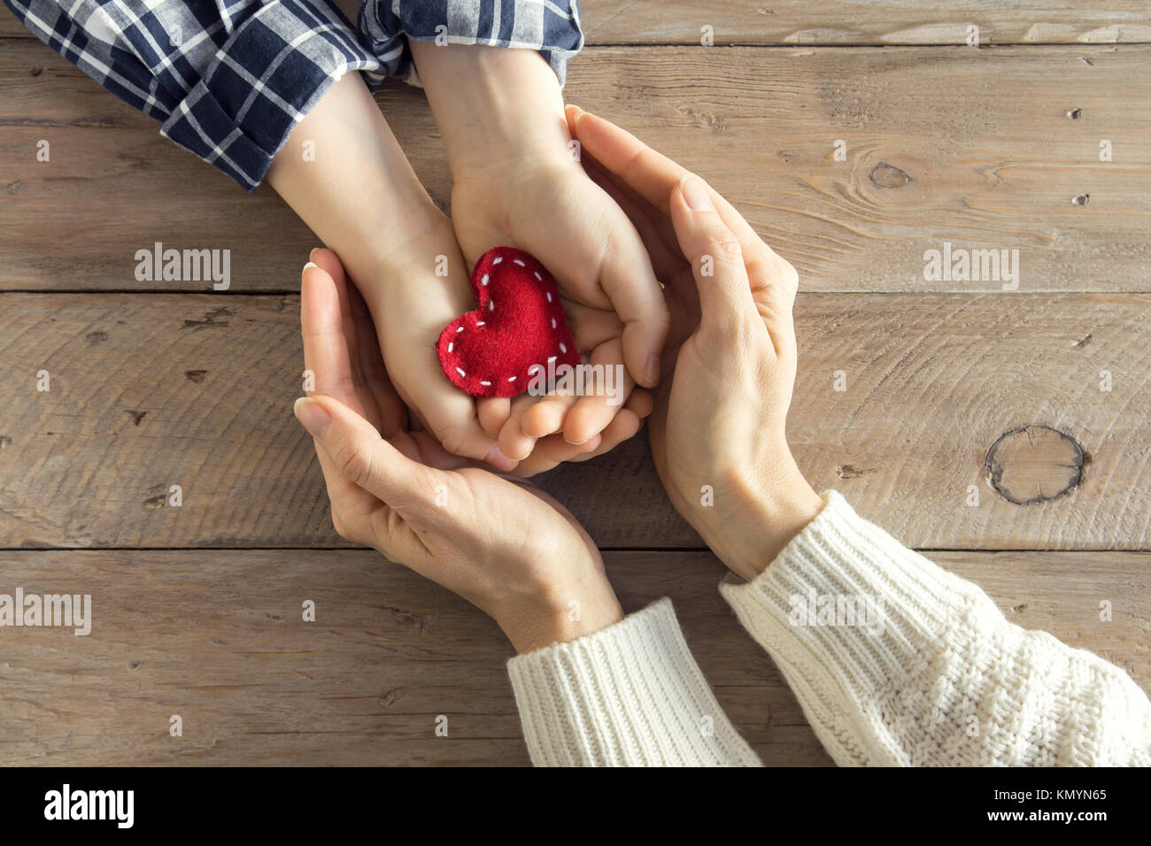 Rotes Herz im Kind und weibliche Hände über Holz- Hintergrund, kopieren. Freundlichkeit, Familie, Liebe und Nächstenliebe Konzept, zum Valentinstag oder Muttertag da Stockfoto