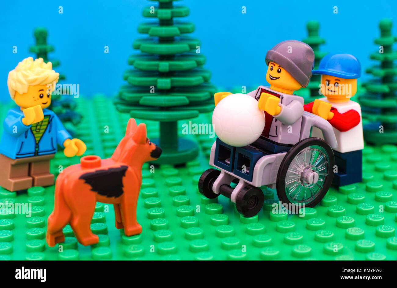 Tambow, Russische Föderation - Juli 30, 2016 Lego Junge im Rollstuhl mit Kugel bereit, mit seinen Freunden und Hund draußen zu spielen. Studio gedreht. Stockfoto
