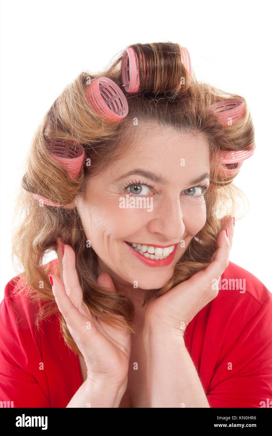 glückliche Frau mittleren Alters in rot mit Lockenwickler - isoliert auf weiss Stockfoto