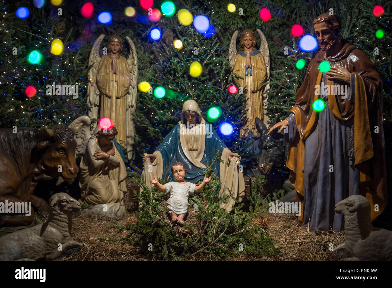 Weihnachten Krippe mit Maria, Josef, der Engel Gabriel und Tiere auf Baby Jesus in seiner Krippe durch Bokeh bunten Lichtern eingerahmt Stockfoto
