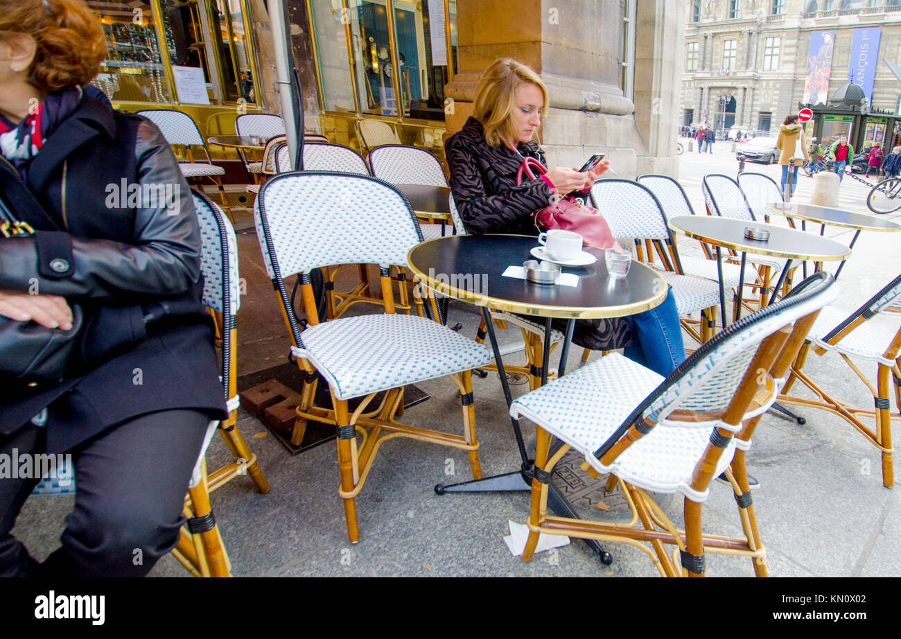 Paris, Frankreich. Palais Royal. Frau prüfen ihr Mobiltelefon in einem Cafe Stockfoto