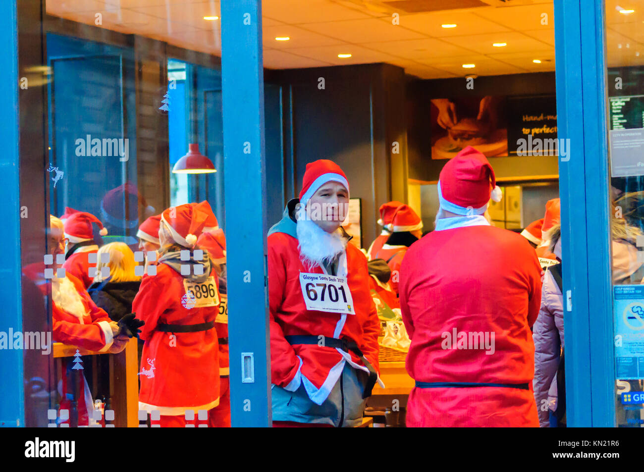 Glasgow, Schottland, Großbritannien. 10. Dezember 2017: Weihnachtsmänner in der Warteschlange an Greggs der Bäcker. Tausende Teilnehmer in Santa Anzüge gekleidet werden, nehmen an der jährlichen Glasgow Santa Strich durch die Innenstadt bei eisiger Kälte - in einem 5k festliche Liebe Fun Run organisiert, um Mittel für gute Zwecke erheben. Nominiert ist in diesem Jahr die Nächstenliebe ist die Beatson Krebs Liebe. Credit: Skully/Alamy leben Nachrichten Stockfoto