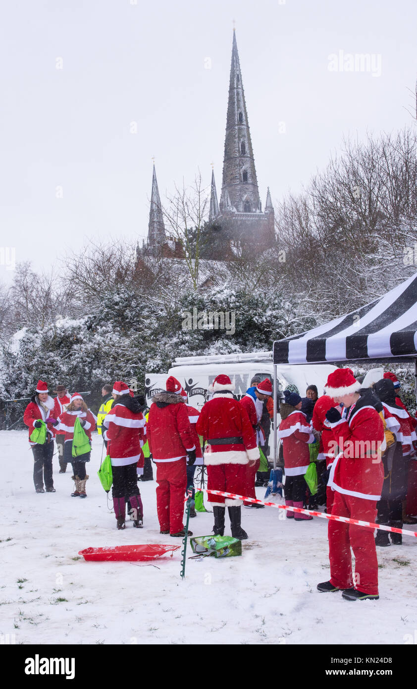 Lichfield, Großbritannien. 10 Dez, 2017. Wettbewerber gekleidet in einem Santa Claus Weihnachtsmann passt am Ende der Lichfield Santa Strich in Stowe Felder in Lichfield, Staffordshire, England mit dickem Schnee auf dem Boden am Sonntag entspannen, den 10. Dezember 2017. Das ist eine jährliche Fun Event. Quelle: David Keith Jones/Alamy leben Nachrichten Stockfoto