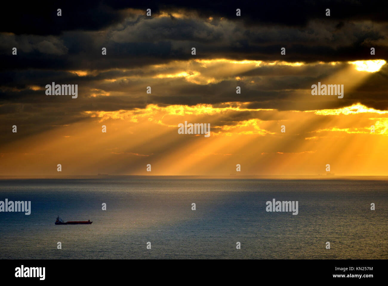 Container schiff leuchtet durch die Strahlen der untergehenden Sonne, Englischer Kanal. Stockfoto