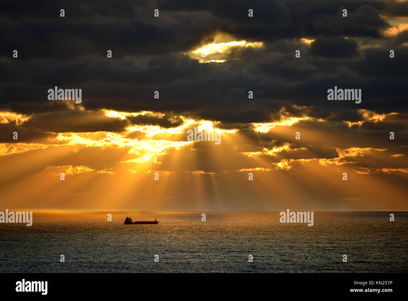 Container schiff leuchtet durch die Strahlen der untergehenden Sonne, Englischer Kanal. Stockfoto