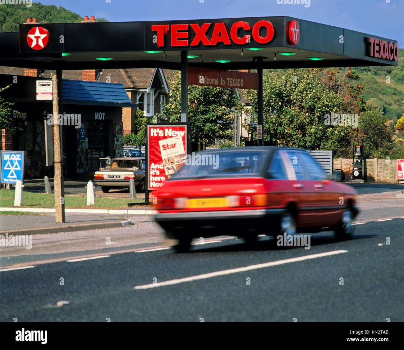 Rotes Auto vorbei an Texaco Tankstelle, Autos und Straßen Stockfoto Rotes Auto vorbei an Texaco Tankstelle, Autos und Straßen Stockfoto