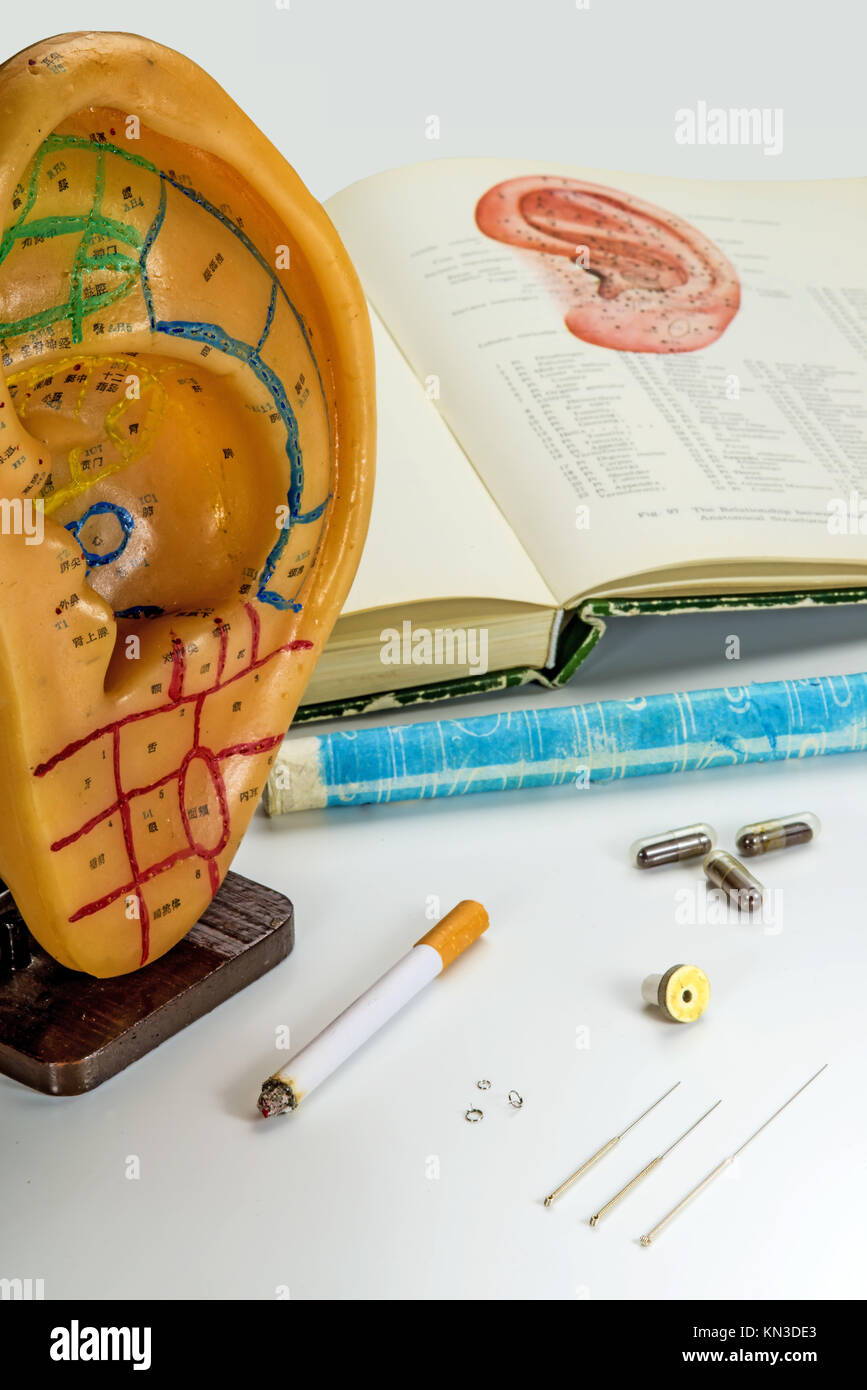 Akupunktur Nadeln, EAR-Modell, Lehrbuch, moxa Kegel und pflanzliche Pillen. Stockfoto