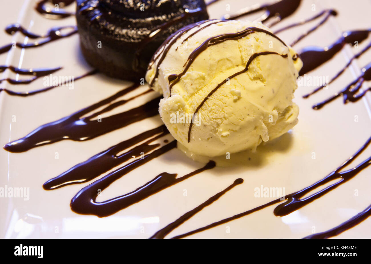 Eine Kugel Vanilleeis mit Schokoladensauce in einer Platte. Stockfoto
