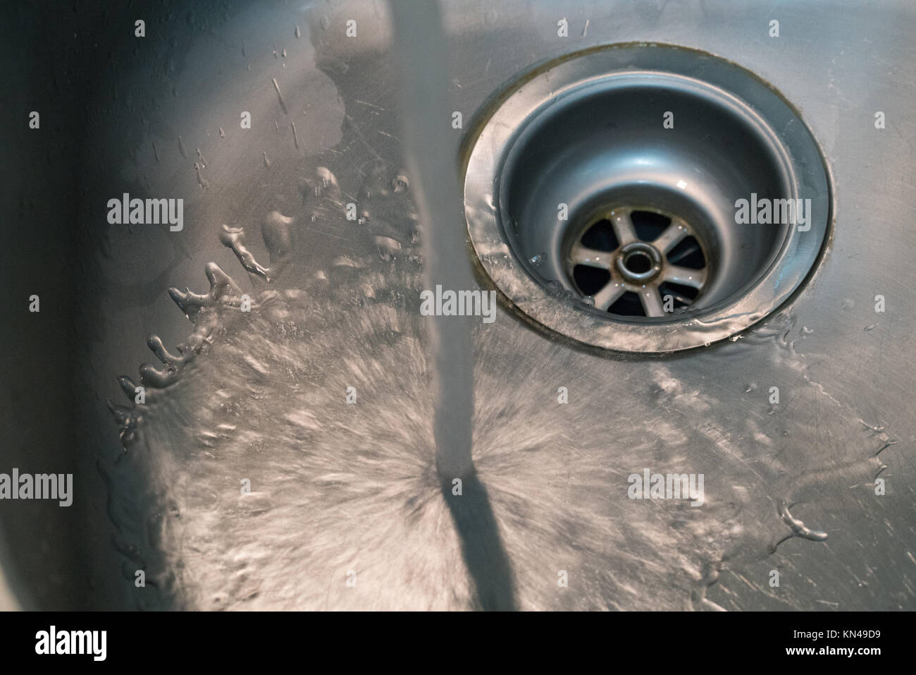 Tippen Sie auf Wasser in ein sauberes Waschbecken mit dramatischen Licht laufen - Verschwendung von Wasser Konzept Stockfoto