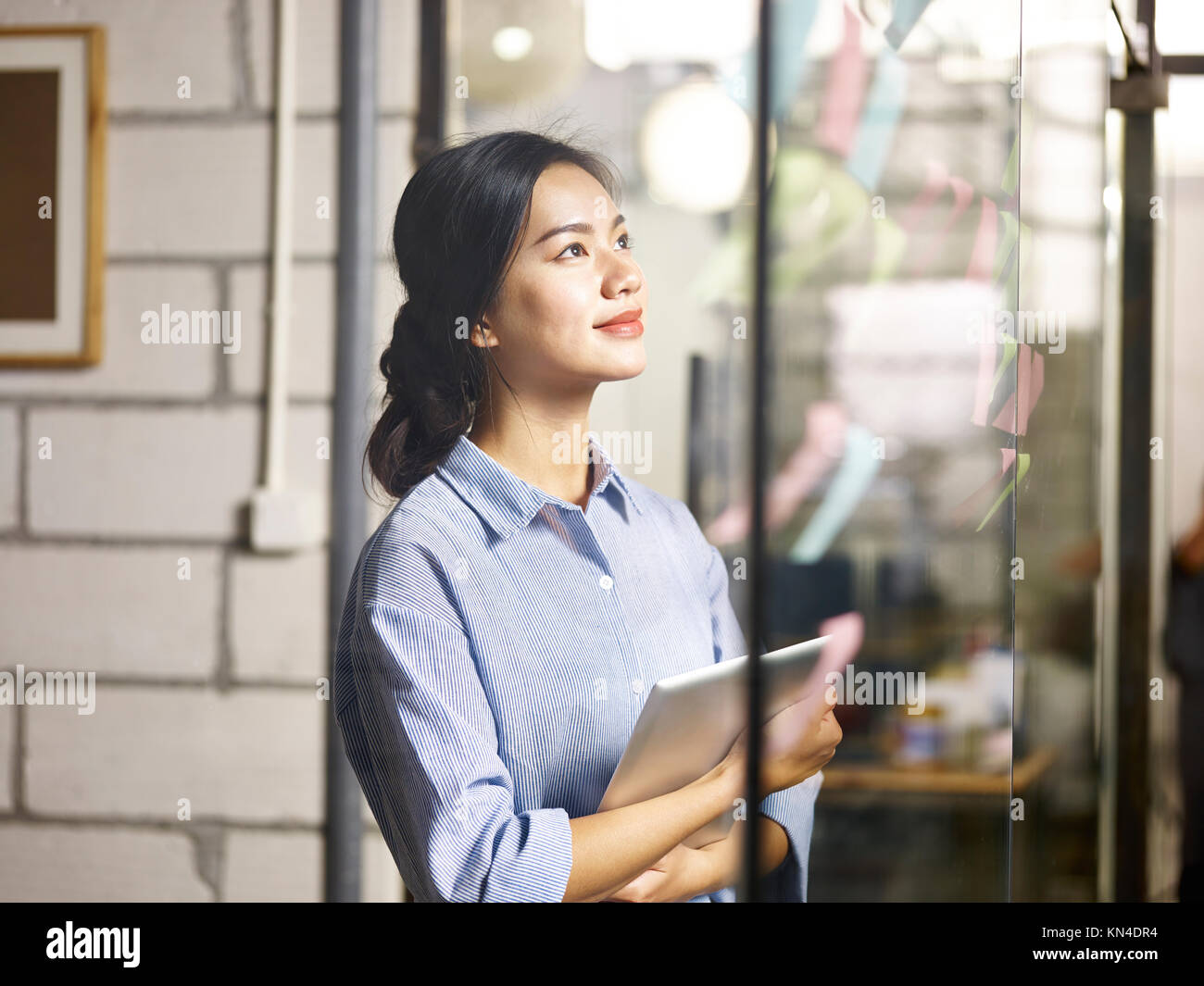 Jungen asiatischen Geschäftsfrau auf Haftnotizen auf Glas Wand während der Business Plan. Stockfoto