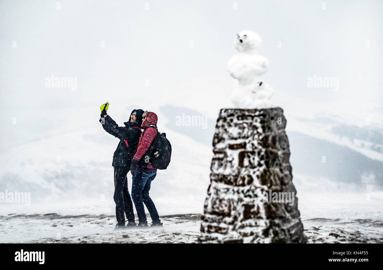 Die Menschen nehmen ein Foto in der Nähe von einem Schneemann auf der "Trig point of Mam Tor im Peak District National Park, wie Schnee und Frost weiter Großbritannien zu schlagen. Stockfoto