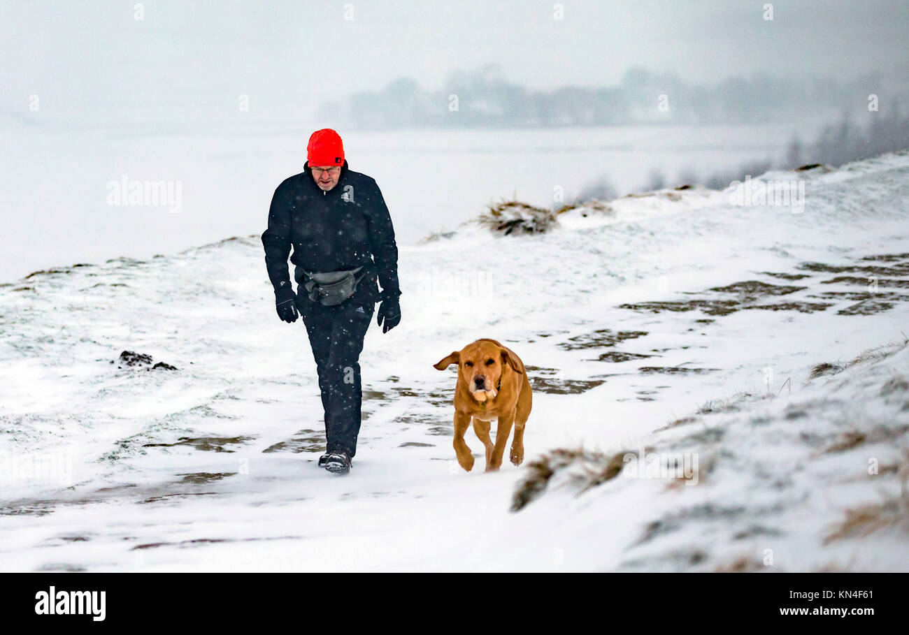 Ein Mann, der seinen Hund in der Nähe von Mam Tor im Peak District National Park, wie Schnee und Frost weiter Großbritannien zu schlagen. Stockfoto
