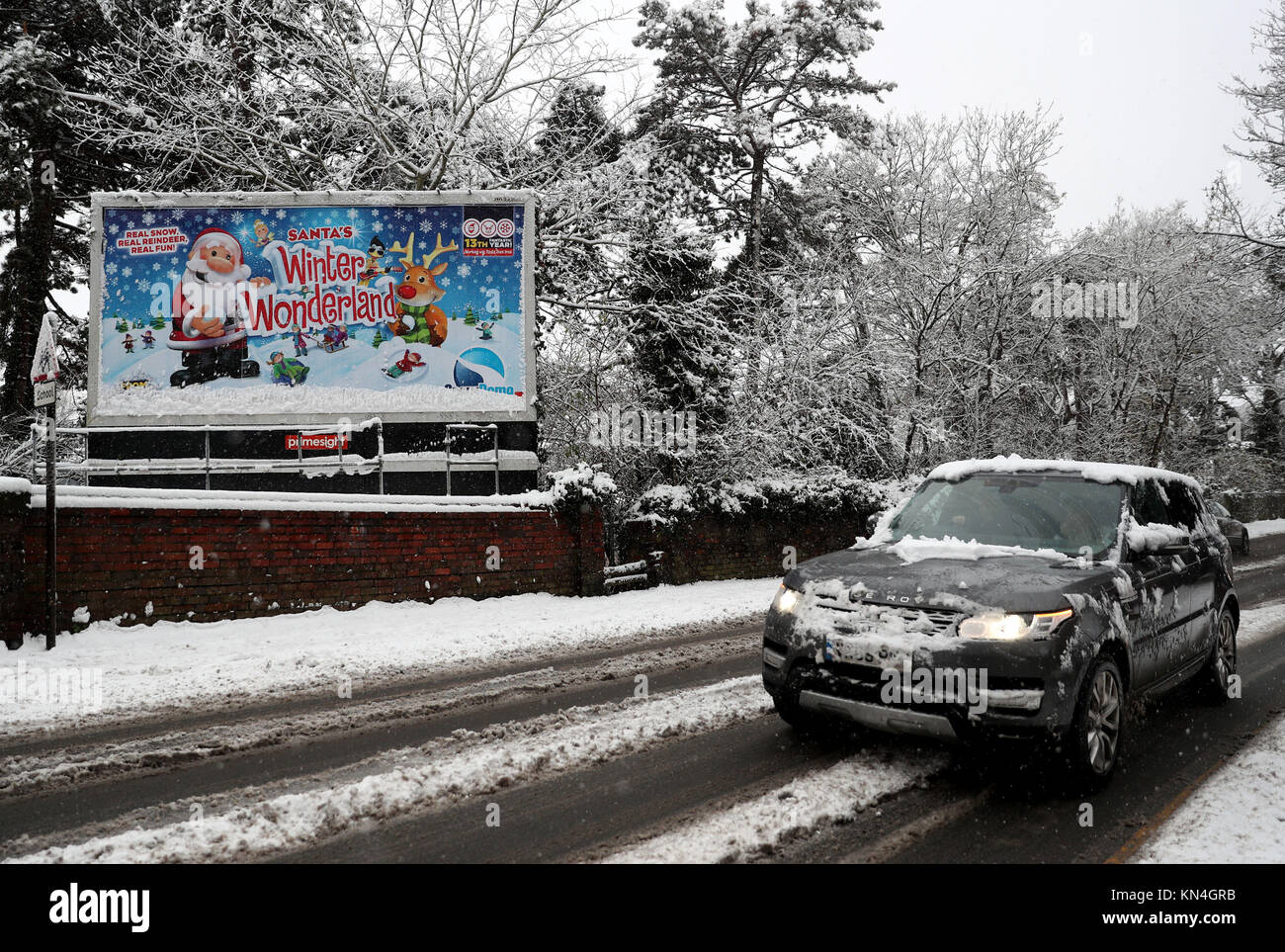 Ein Auto fährt vorbei an einem verschneiten Zeichen Werbung Santa Winterlandschaft in Worcester, wie starker Schneefall über Teile von Großbritannien weitverbreitete Störungen verursacht, schließen Straßen und Erdung Flüge am Flughafen. Stockfoto