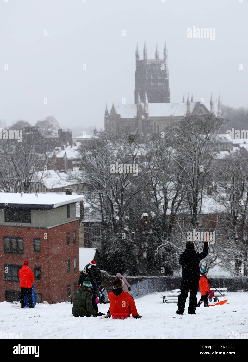 Menschen Schlitten hinunter einen Hügel mit Blick auf die Kathedrale von Worcester, wie starker Schneefall über Teile von Großbritannien weitverbreitete Störungen verursacht, schließen Straßen und Erdung Flüge am Flughafen. Stockfoto