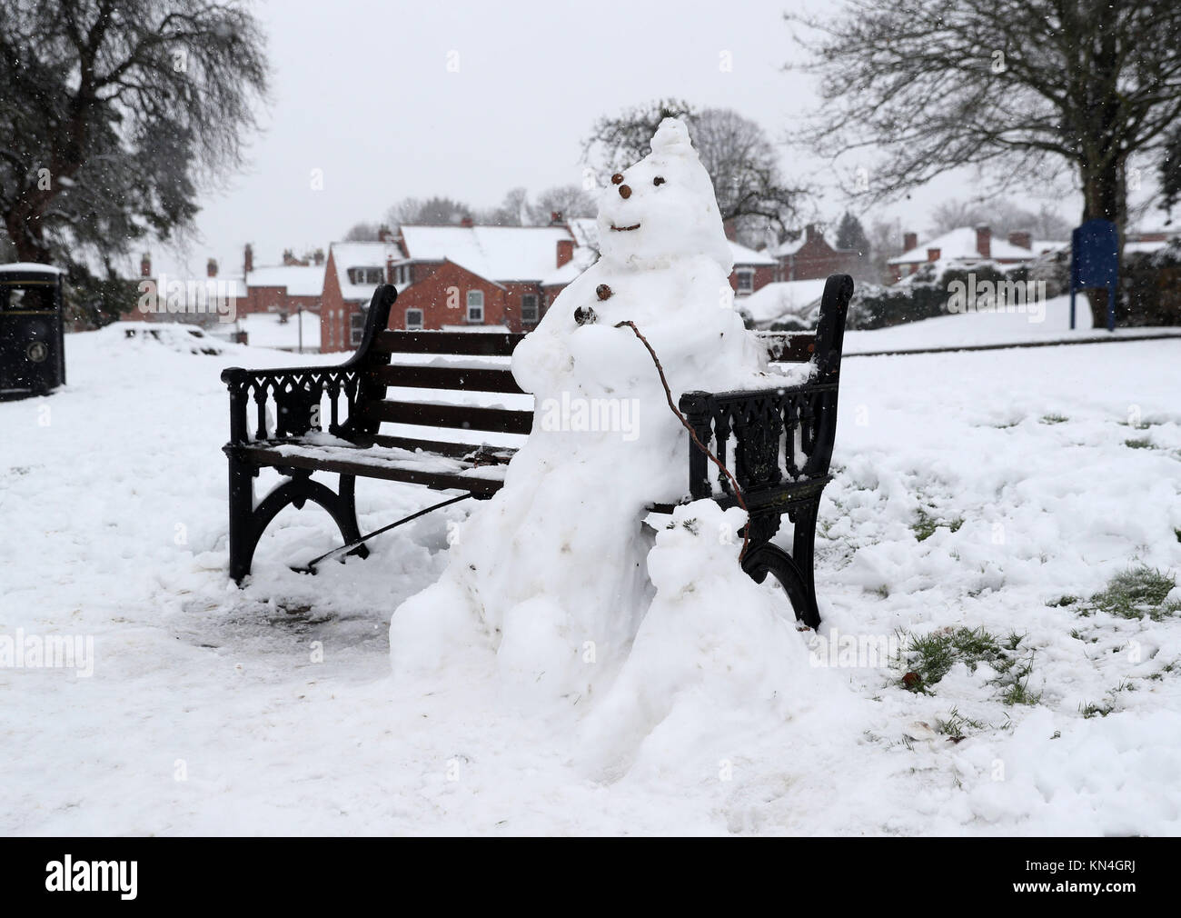 Ein Schneemann auf einer Bank, Worcester, wie starker Schneefall über Teile von Großbritannien weitverbreitete Störungen verursacht, schließen Straßen und Erdung Flüge am Flughafen. Stockfoto