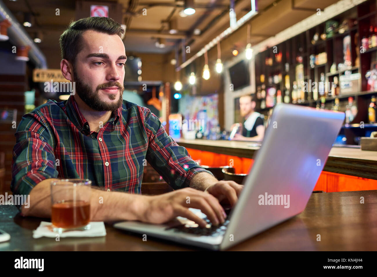 Junger Mann mit Laptop im Pub Stockfoto