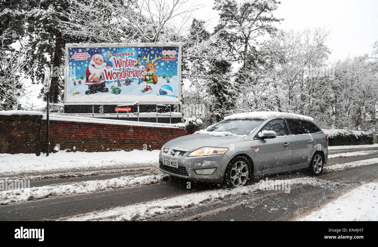 Ein Auto fährt vorbei an einem verschneiten Zeichen Werbung Santa Winterlandschaft in Worcester, wie starker Schneefall über Teile von Großbritannien weitverbreitete Störungen verursacht, schließen Straßen und Erdung Flüge am Flughafen. Stockfoto