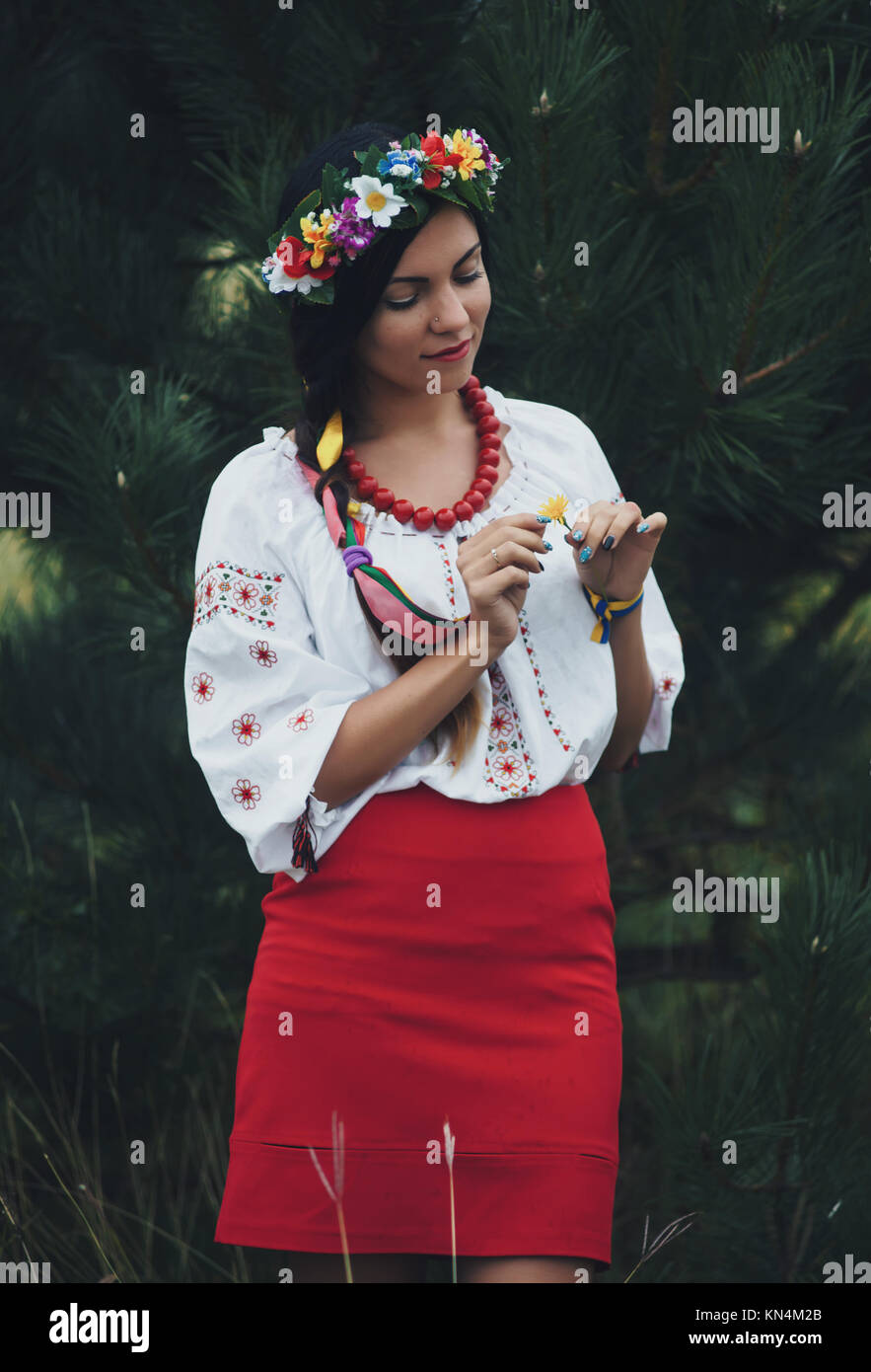 Schöne Frau in bunten ukrainischen Tracht halten Sie sich selbst und genießen Sie Sommer im grünen Wald Stockfoto