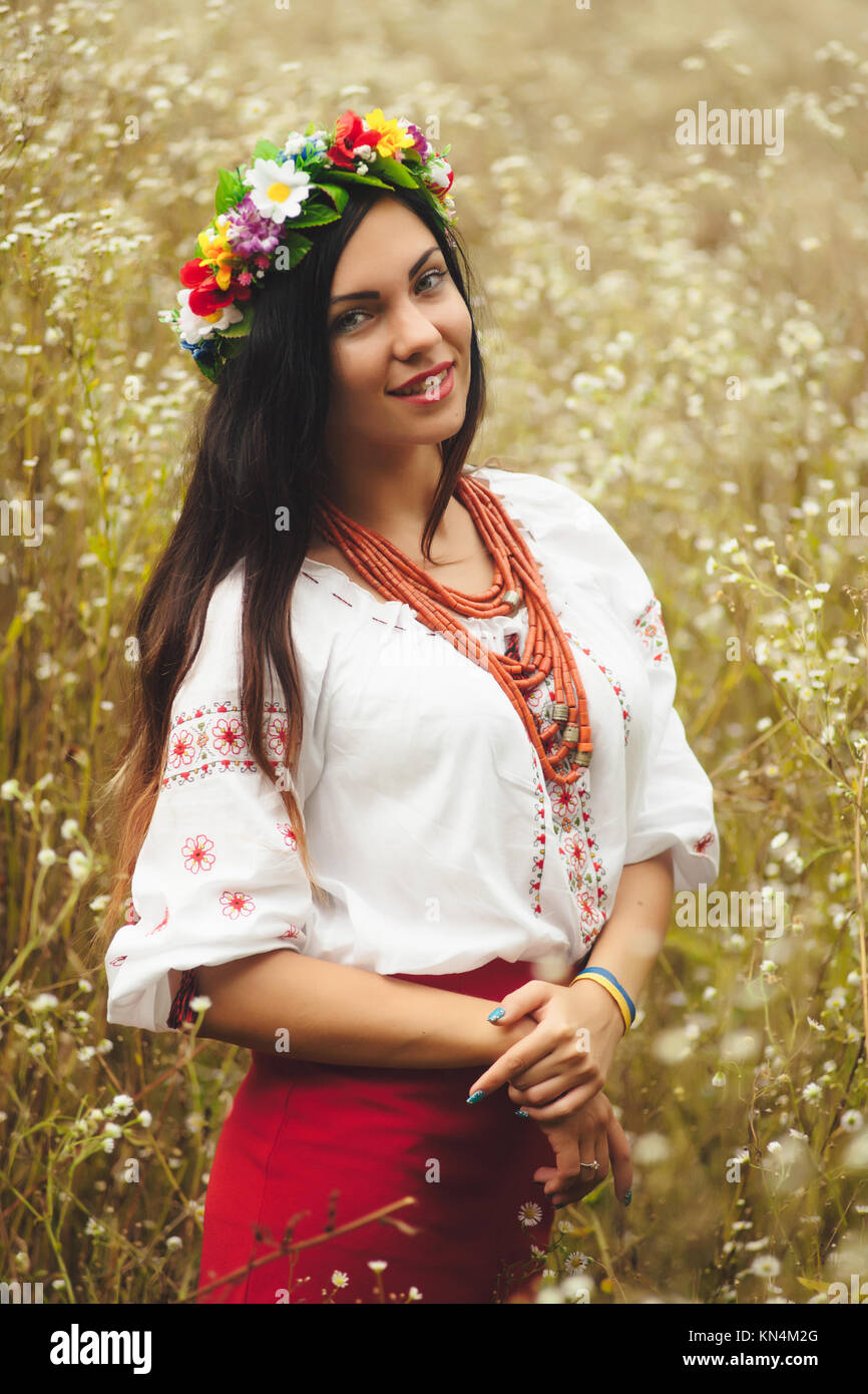 Schöne Frau in bunten ukrainischen Tracht halten Sie sich selbst und genießen Sie Sommer im Feld Stockfoto