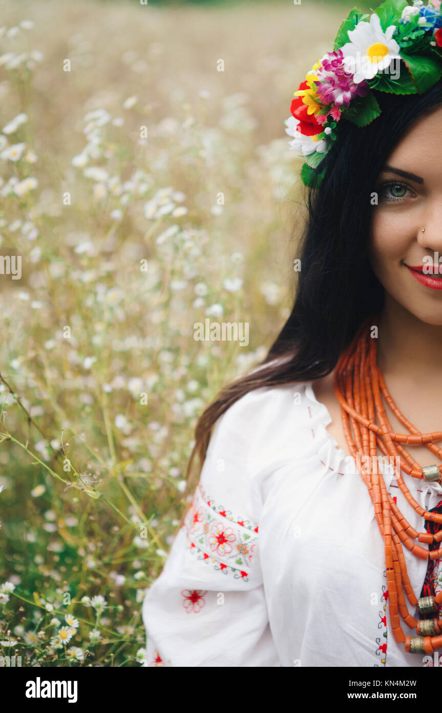 Schöne Frau in bunten ukrainischen Tracht halten Sie sich selbst und genießen Sie Sommer im Feld Stockfoto