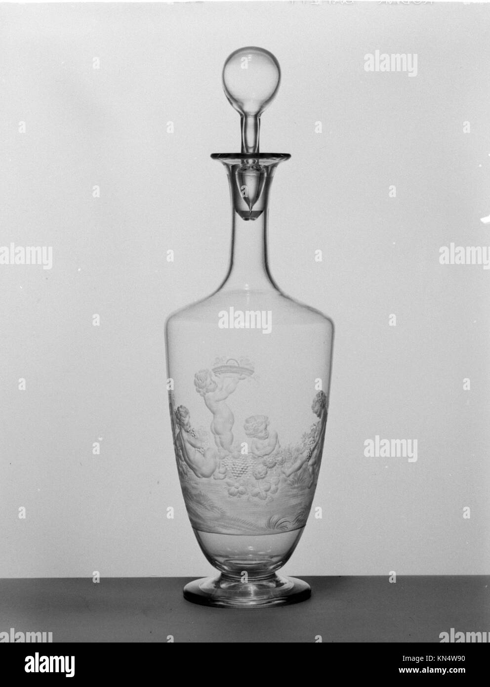 Eine Karaffe mit gemalten oder geätzten Bildern von Kindern, die im Herbst Trauben ernten, die als dekoratives Glas- oder Keramikgefäß aufbewahrt werden. Stockfoto