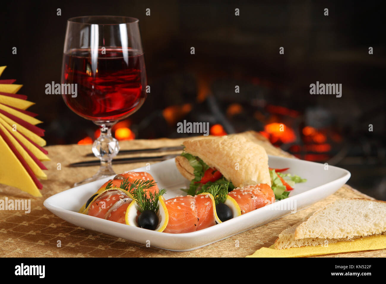 Leckeres Abendessen auf einem Tisch gegenüber einem Kamin Stockfoto