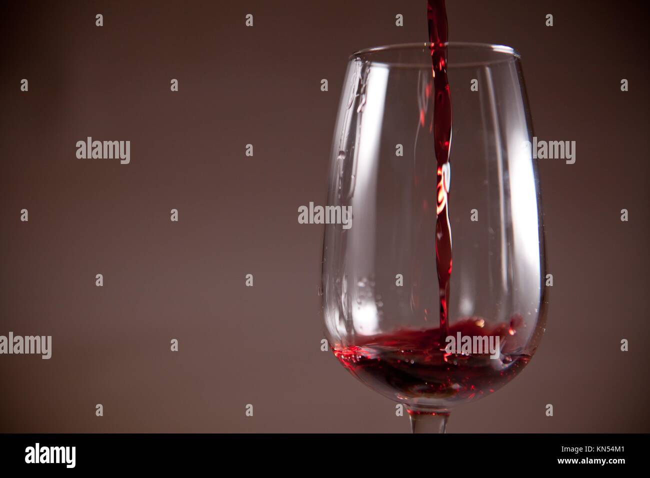 Glas mit rotem Wein eingeschenkt auf eine Tasse. Über dunklen Hintergrund isoliert. Stockfoto