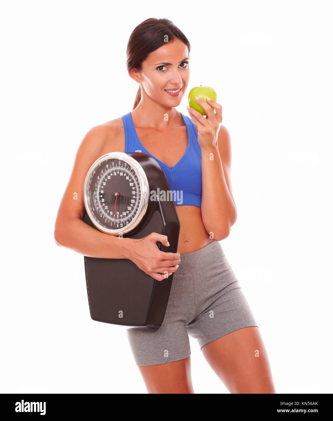 Sportliche junge Frau essen Apple, Gewicht zu verlieren und Sie gegen den weißen Hintergrund. Stockfoto